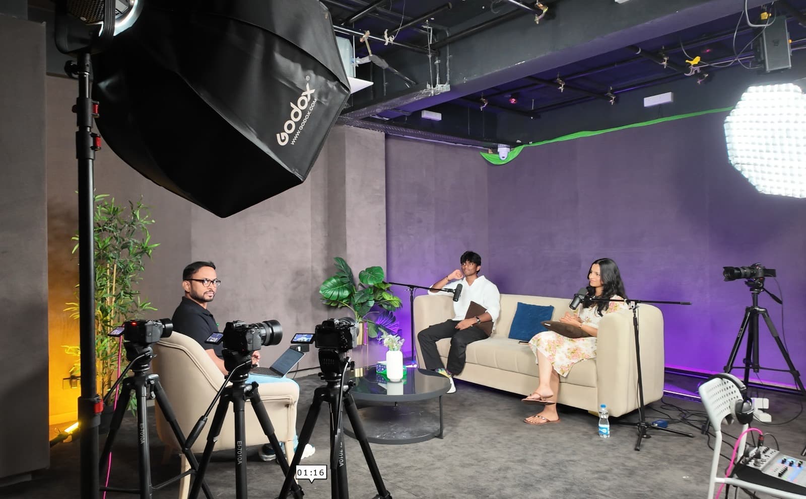 Wide studio shot — full podcast set with cameras, lighting, and guests